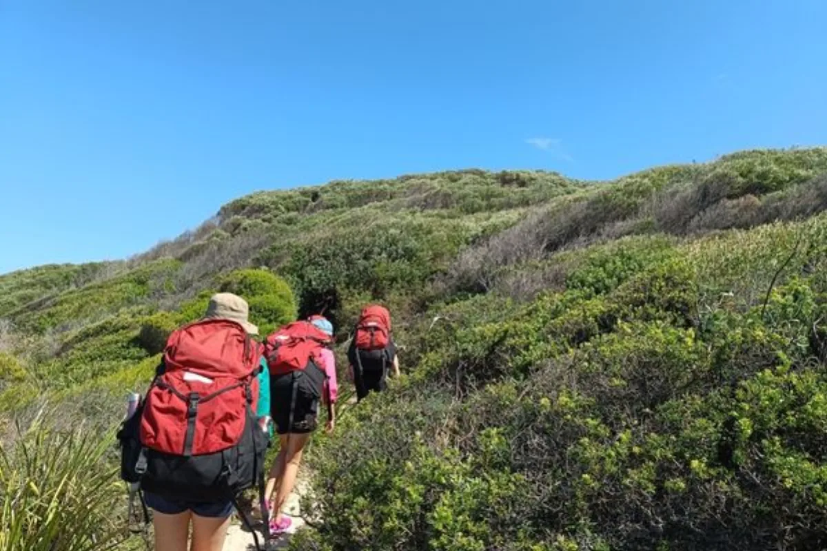 Young people hiking a coastal trail with packs on a Southbound journey
